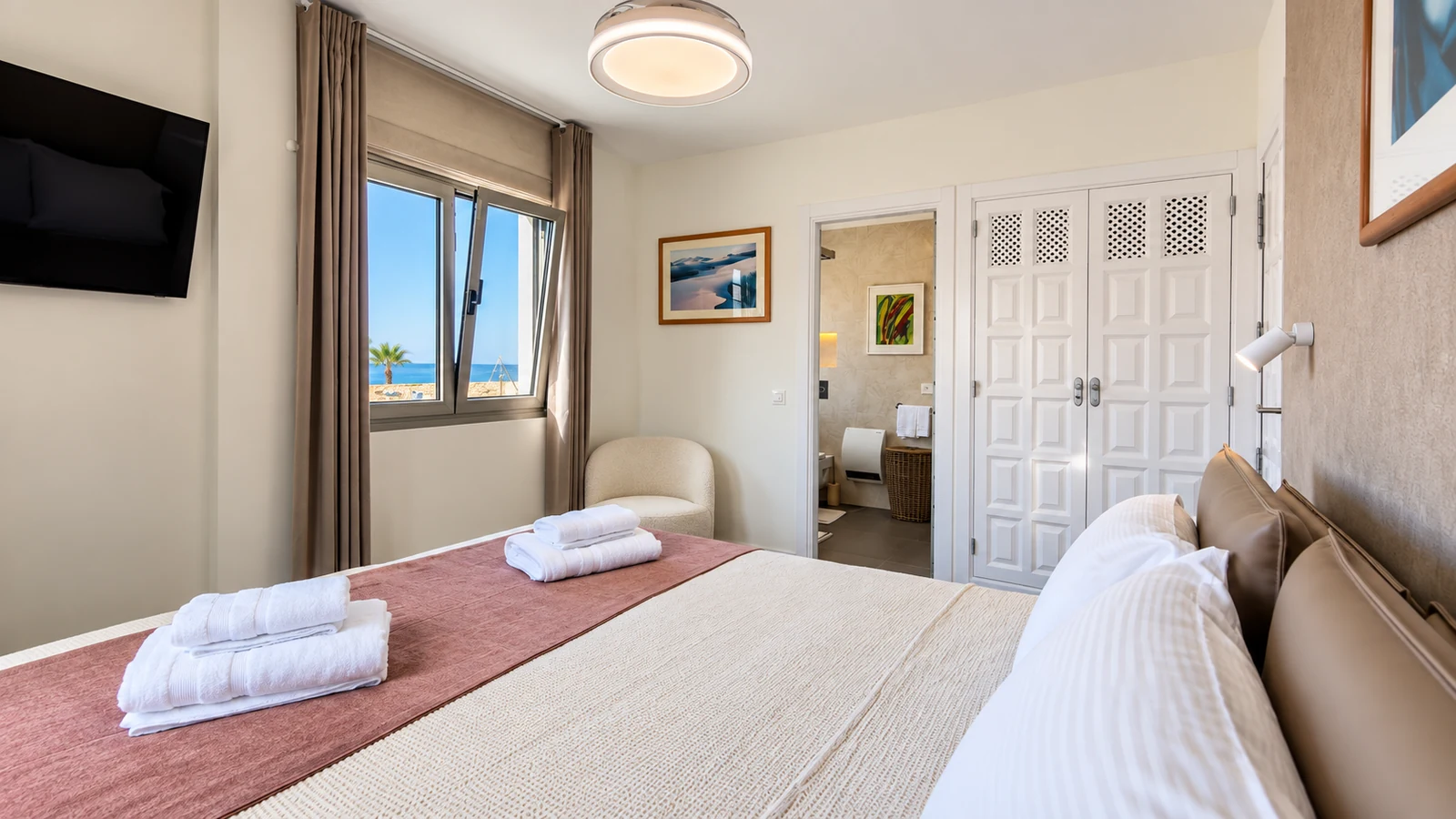 Bedroom with ocean-view window and en-suite doorway at Villa White Octopus